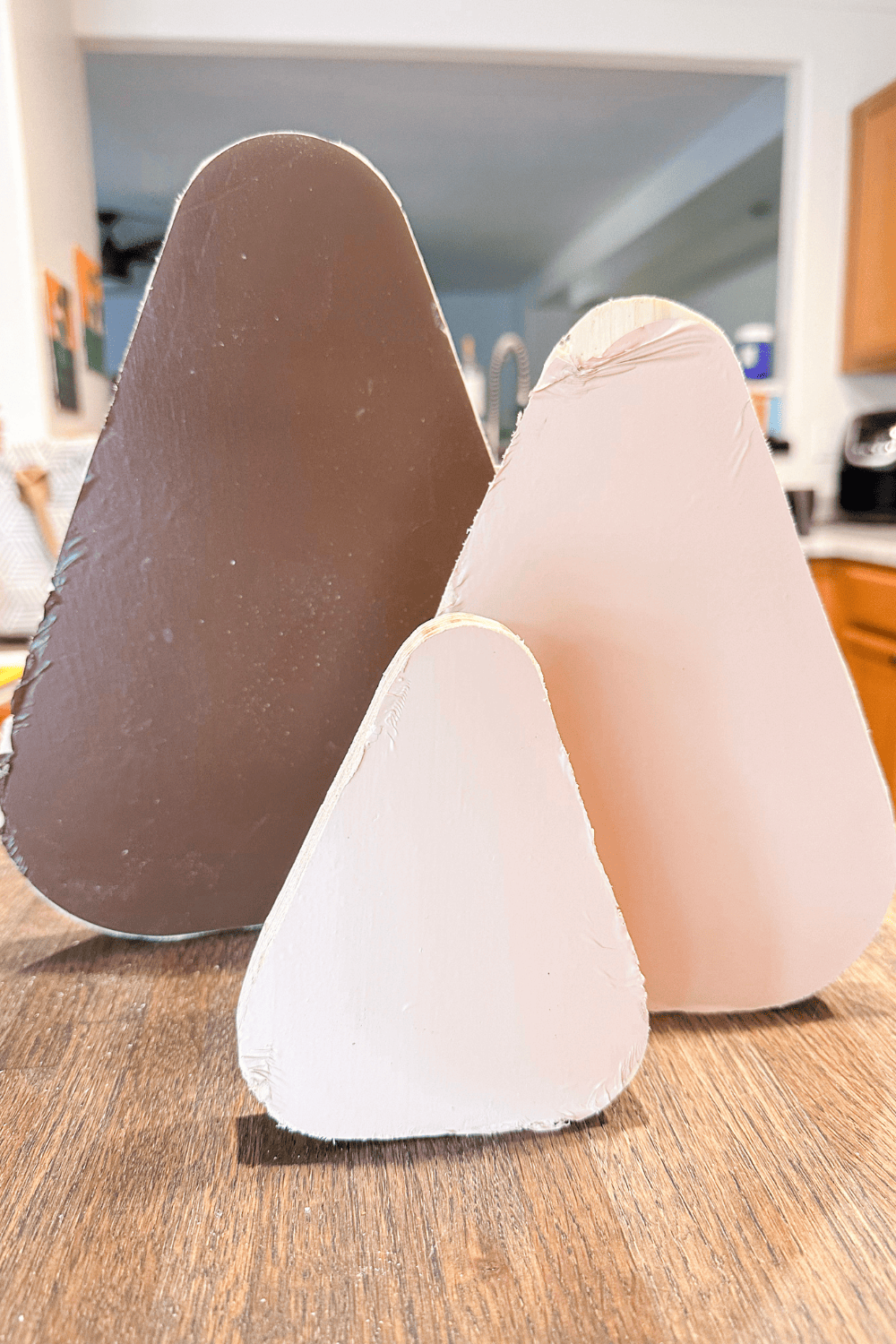 3 different sized candy corn shapes. The largest one in the back with brown vinyl. The smaller 2 in the front with pink vinyl.