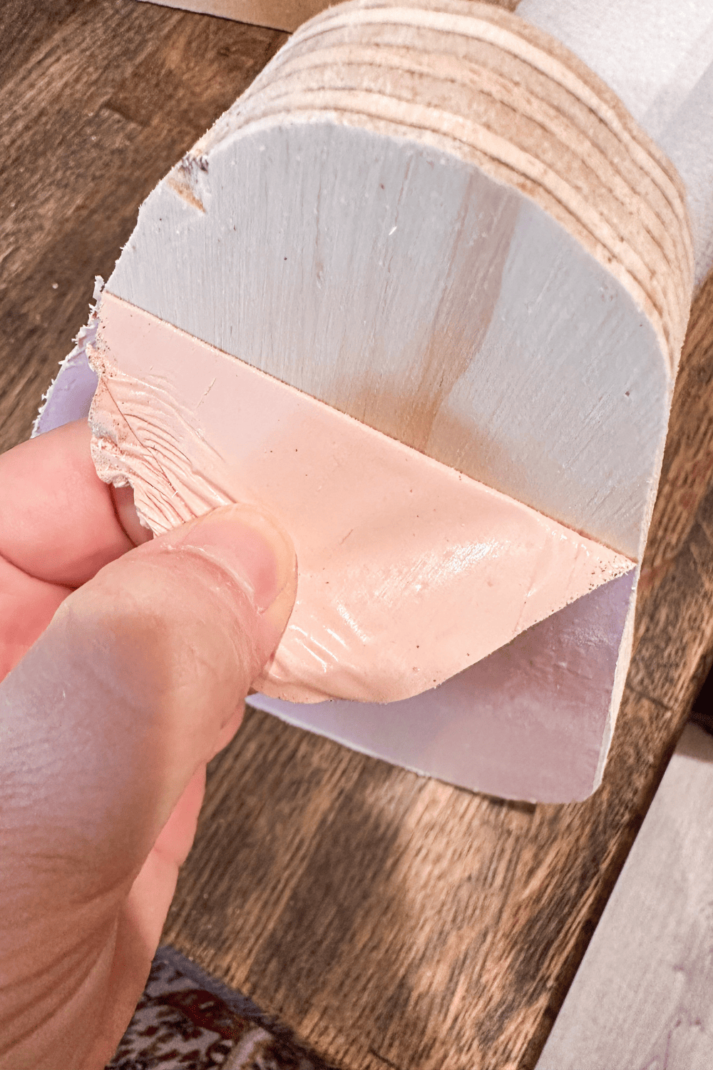 Hand peeling pink vinyl off of plywood