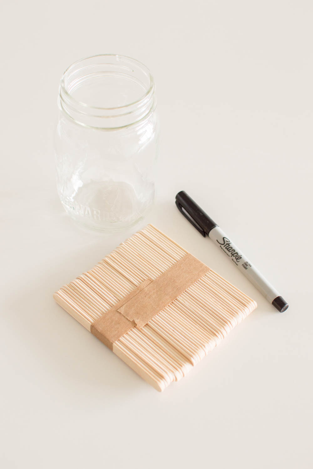 Supplies required to make a date night jar including popsicle sticks, permanent marker and a mason jar