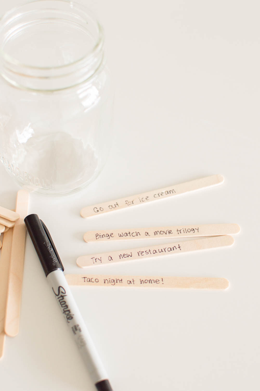 Writing date ideas on popsicle sticks on a white table