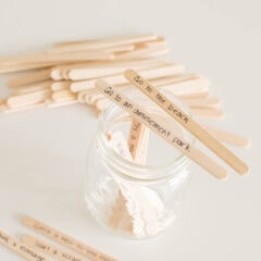 Two popsicle sticks with writing propped on the top of an open mason jar