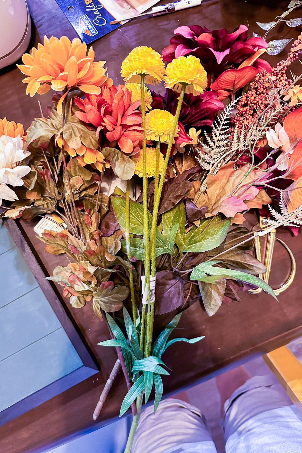 bundle of fake flowers in shades of orange, red, and yellow, with fall leaves and berries.