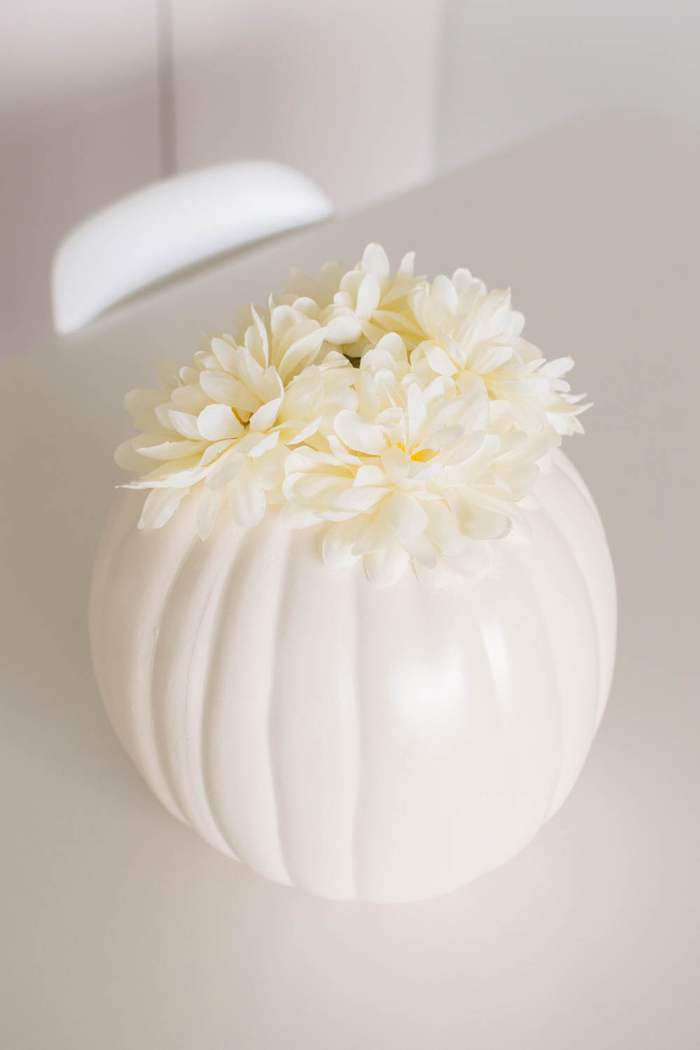 White faux flowers glued on a white plastic pumpkin for white pumpkin decor