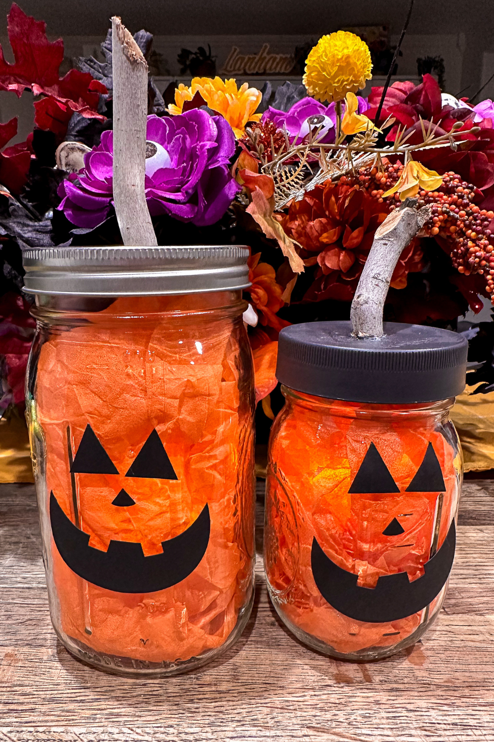 2 mason jar pumpkins sitting next to each other with fake flowers in the background