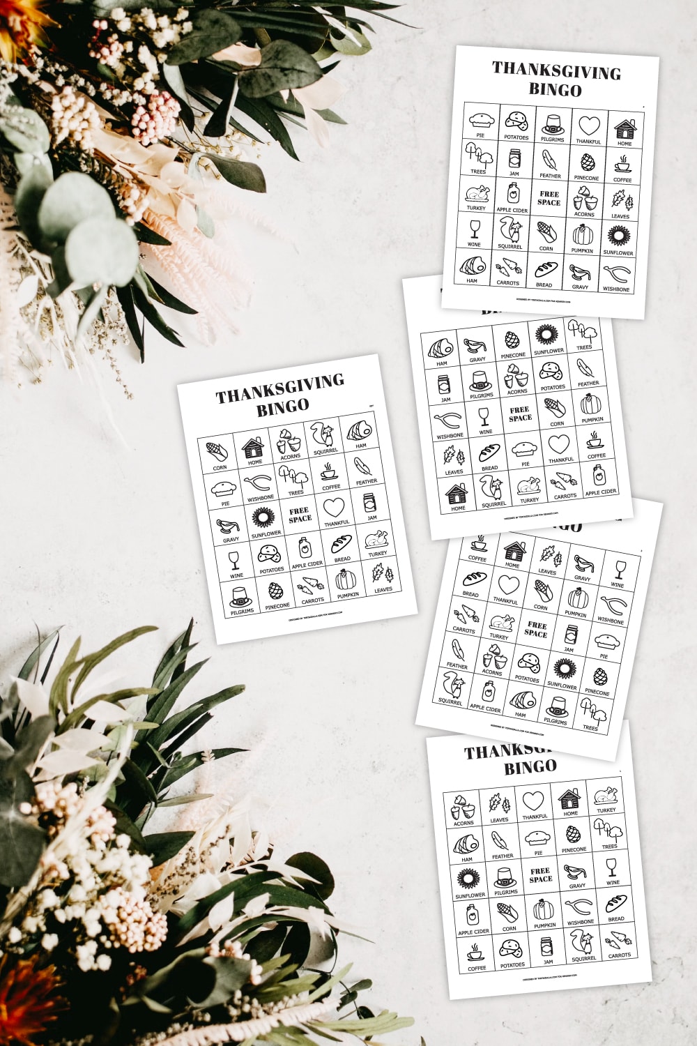 Preview of printable bingo pages on marble countertop with dried foilage decorations in upper left and lower left. 