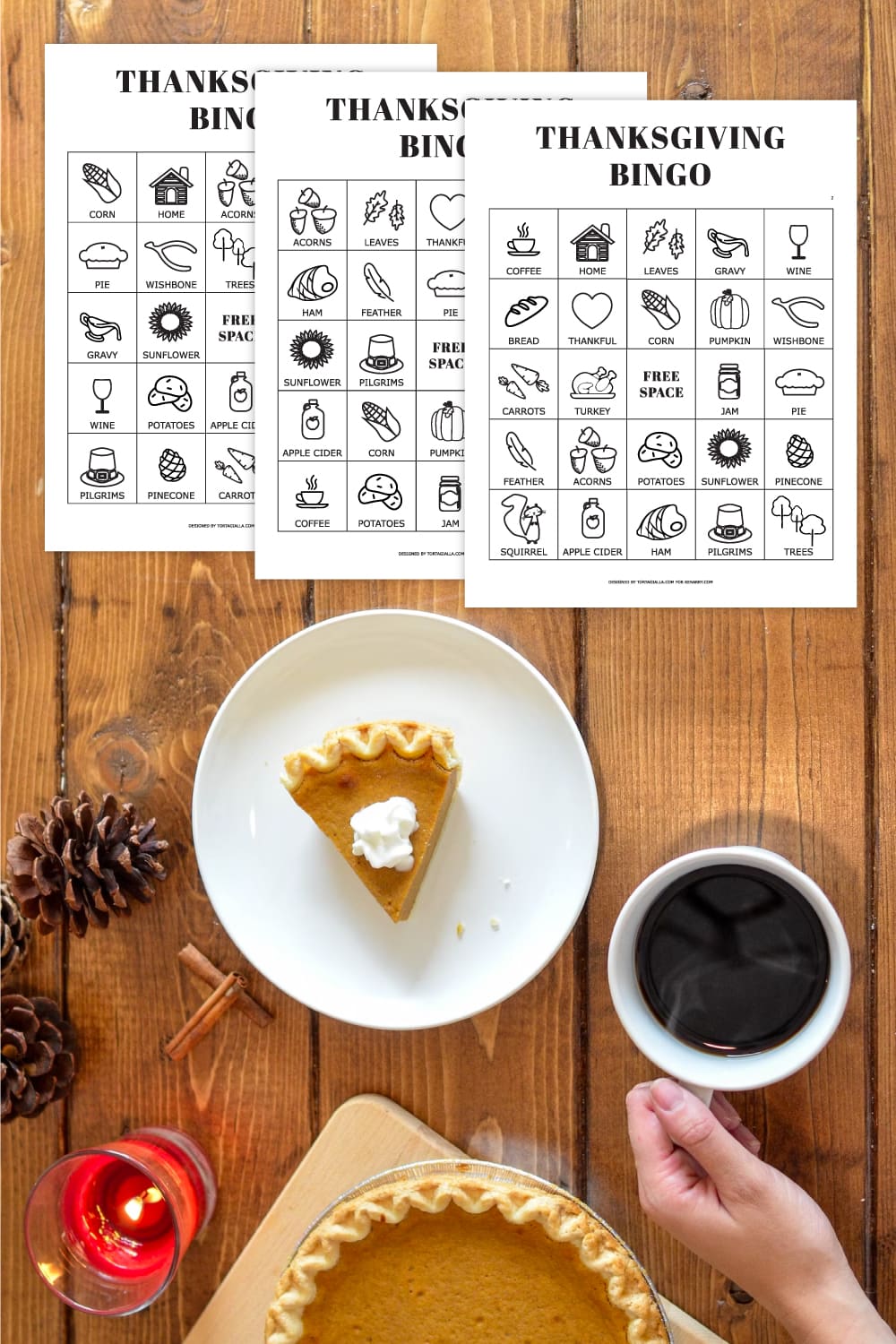 Preview of printable bingo pages with Thanksgiving icons on wooden tabletop with white plate and slice of pie on bottom with hand holding cup of coffee and pinecones and candle burning in lower left. 