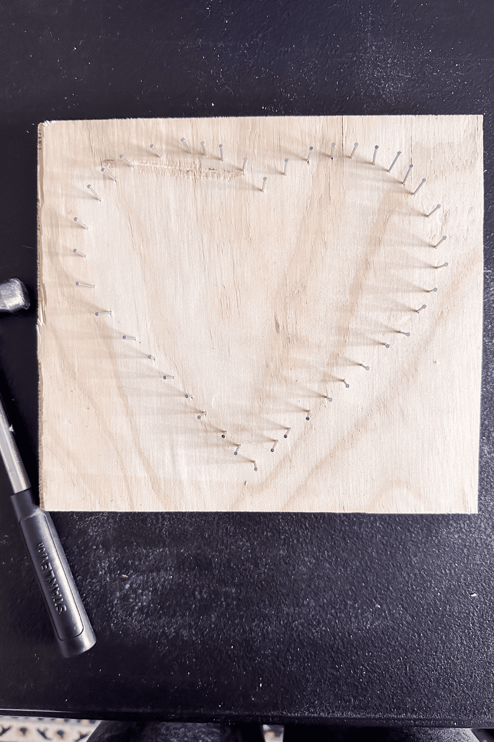 Nails on a piece of wood in the shape of a heart