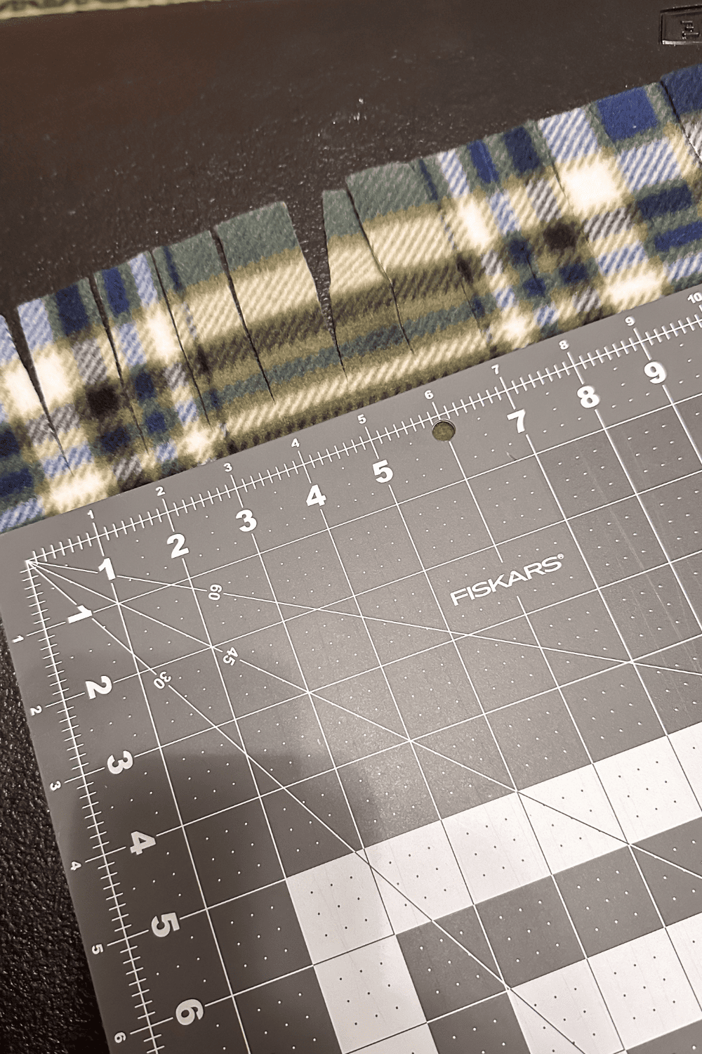 cutting mat on top of a green plaid scarf with cuts every one inch