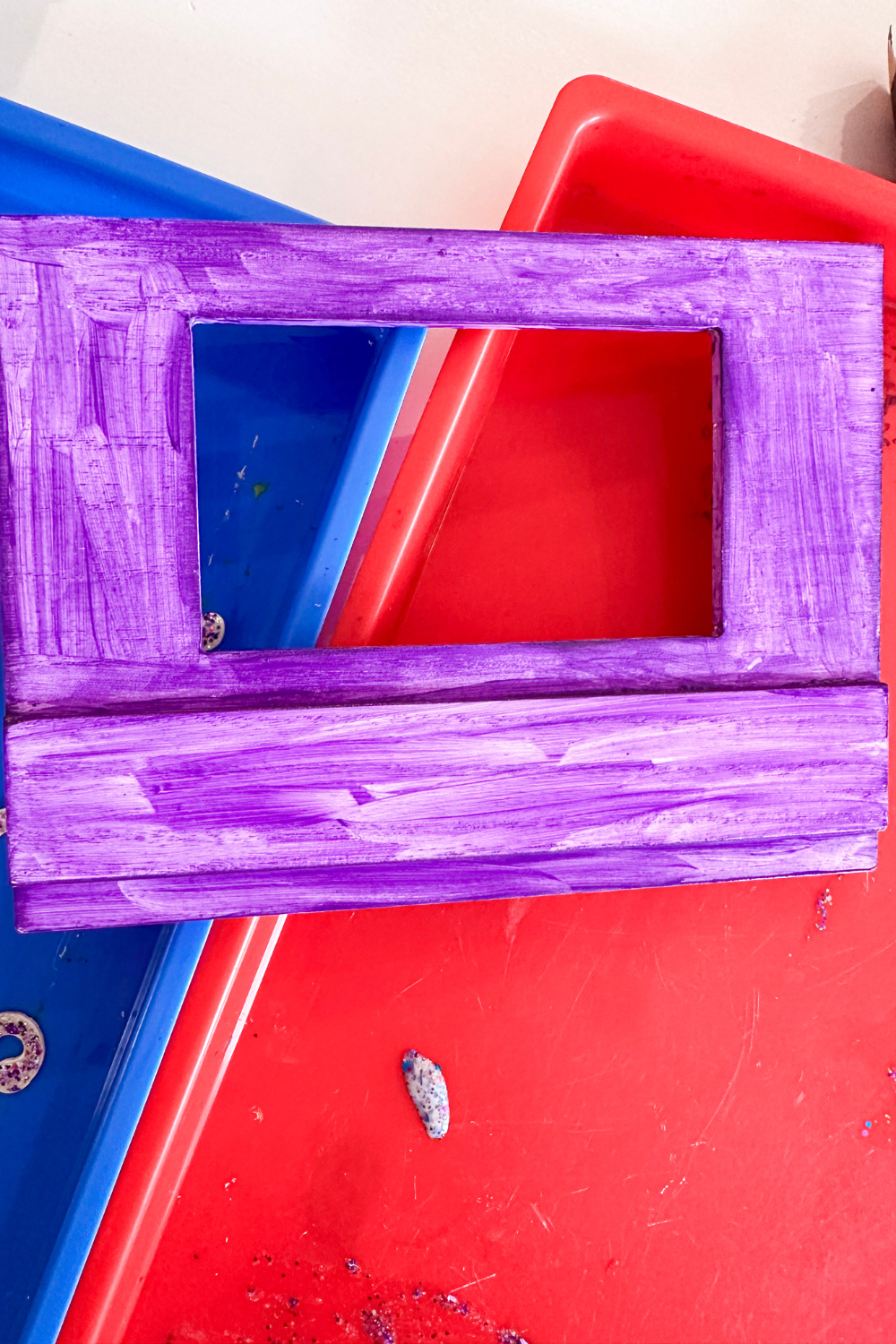 Picture frame with one coat of purple paint. The paint is streaky.