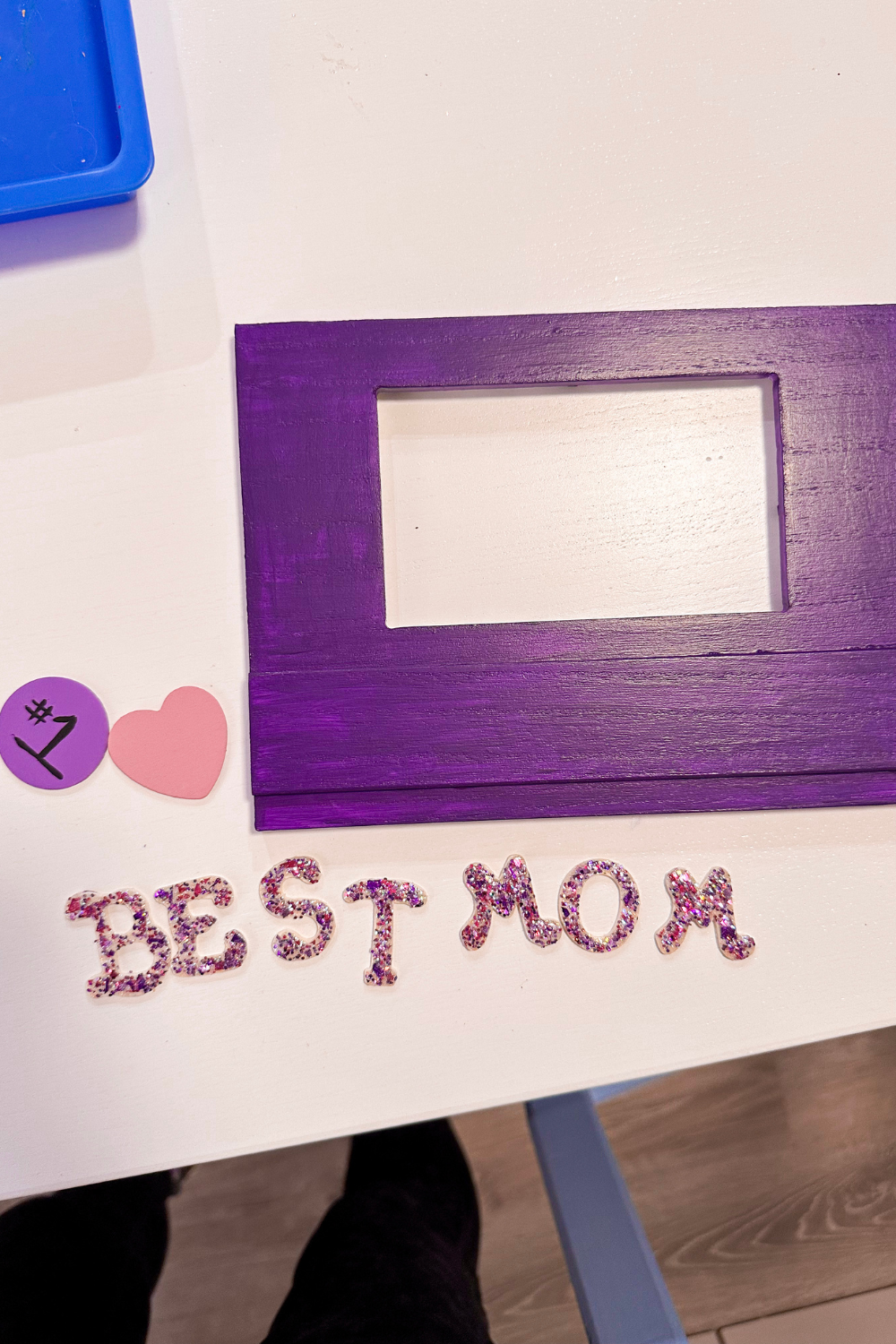 picture frame painted purple on the right side, on the left a heart painted pink and a circle painted lavender with a #1 in black. Best Mom wood letters with glitter paint on the bottom